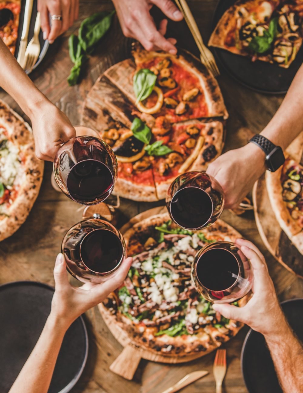 people-clinking-glasses-over-table-with-italian-pizza-square-crop.jpg